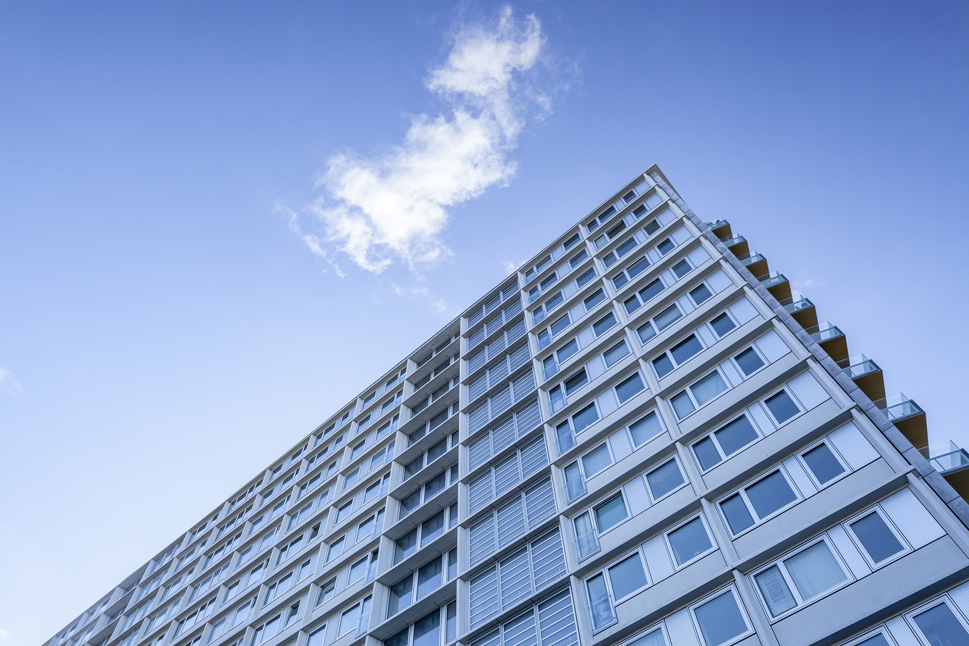 A low angle shot of a big building under a cloud in the beautiful blue sky